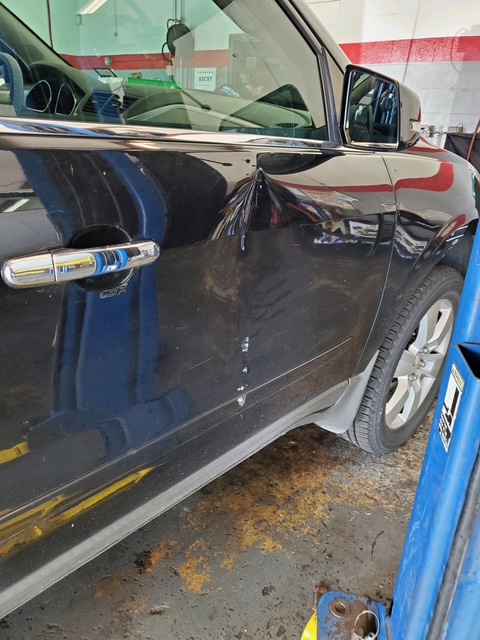 Black door with a sharp crease beneath the window before repair
