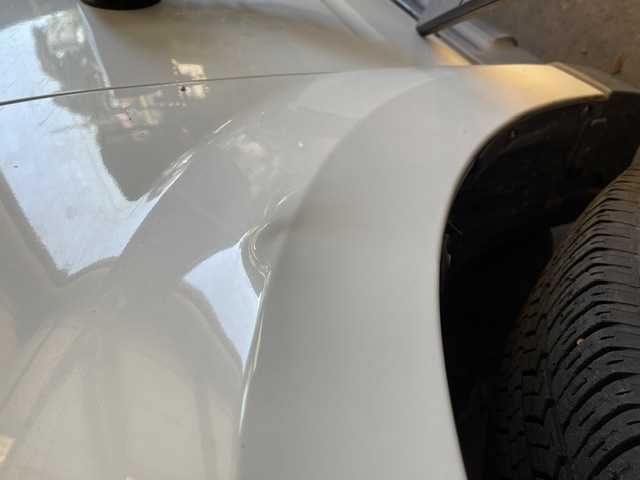 White front fender with a dent above the wheel arch